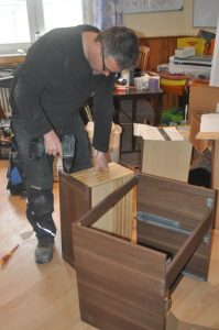 Chris assembling cabinets with instructions in German